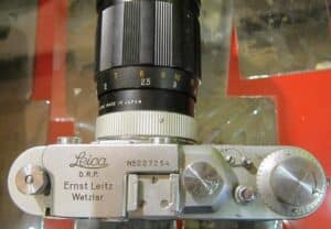 Kolekcjonerski aparat fotograficzny Leica 4 z japońskim obiektywem na tle, widok z przodu i z boku.