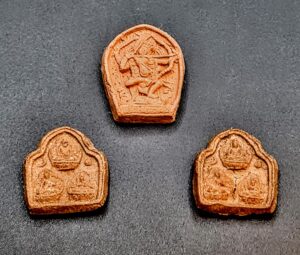 Ceramiczna buddyjska plakietka amulet z Mongolii z XX wieku, pokazująca religijny symbol lub wizerunek.