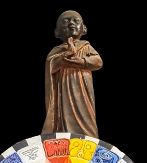 Ceramiczna figura buddyjska z Bhutanu, XX wiek, widok z przodu pokazujący detale szat i spokojną pozę.