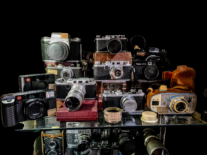 Kolekcja vintage aparatów fotograficznych na tle starej mapy - Leica, Alfa i inne modele