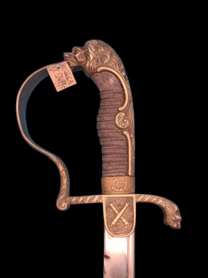 Pruska szabla paradna artylerii z XIX wieku, stalowe ostrze, ozdobna rękojeść na ciemnym tle.