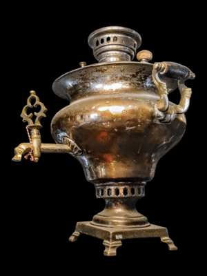 Zabytkowy mosiężny samowar z Tuły z XIX wieku, typ medalowy, na drewnianym tle.