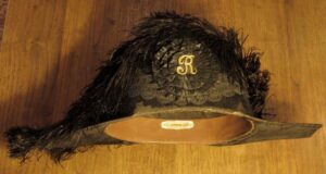 Antyczny srebrny amulet ochronny z inskrypcją Amos Swori Company na ciemnym tle.