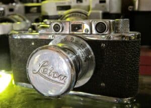 Zabytkowy, czarny aparat fotograficzny Leica II z lat 30. XX wieku na tle neutralnym