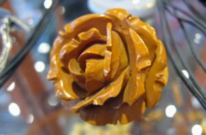 XIX-wieczna broszka z ciemnego bakelitu w kształcie ręcznie rzeźbionej róży z żółtą imitacją bursztynu w środku.