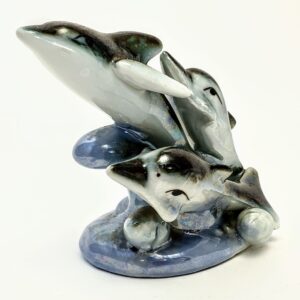 Vintage ceramiczna figurka trzech delfinów z opalizującym, błękitnym szkliwem na białym tle