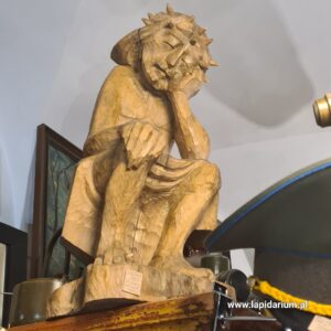 Duża drewniana rzeźba Jezusa Frasobliwego w stylu szkoły zakopiańskiej, XX wiek, widok z przodu.