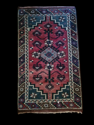 Ręcznie tkany mały dywanik nomadyczny o etnicznych wzorach, widok z góry na tkaninę.