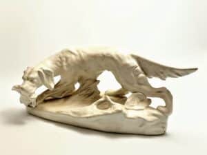 Biała porcelanowa figurka psa myśliwskiego setera trzymającego ptaka w pysku – Royal Dux Bohemia.