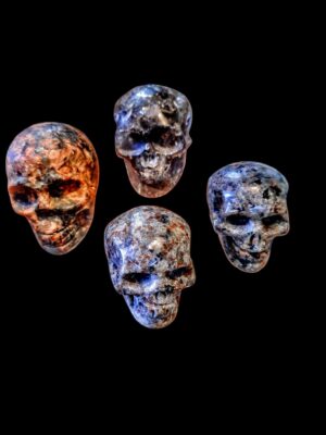 Ręcznie rzeźbione miniaturowe czaszki z naturalnego kamienia na tle, amulety etniczne.