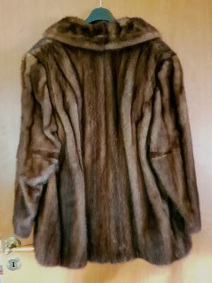Nieużywana, luksusowa kurtka wierzchnia z naturalnego futra norek na wieszaku, widok z przodu.