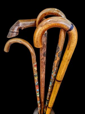 Zabytkowa, drewniana laska turystyczna z kilku metalowymi plakietkami z nazwami miejscowości lub szlaków.