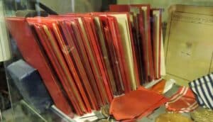 Kolekcja oryginalnych, historycznych legitymacji i dokumentów nadania odznaczeń na tle zielonego sukna.