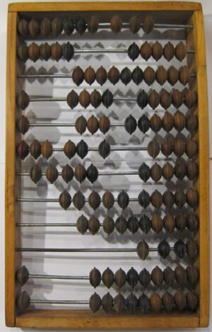 Drewniane liczydło z lat 50. XX wieku, polskiej produkcji, na tle starego drewna.