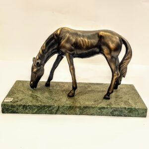 Masywna figura konia odlana z mosiądzu, stojąca na ciężkiej, marmurowej podstawie. Widok z przodu.