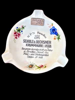Porcelanowa popielniczka reklamowa KPM Berlin w kolorze białym, widok z boku z widocznym logo.