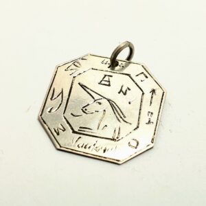 Srebrny amulet magiczny Talizman V z ręcznym grawerunkiem z pracowni Mistrza Kilińskiego na ciemnym tle.