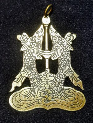 Srebrny amulet wisior z buddyjskim symbolem Złotych Ryb (Gaur-Matsya) na ciemnym tle.