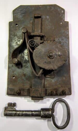 Stary, kuty zamek do drzwi z dużym, oryginalnym kluczem na tle drewna - antyk z Dolnego Śląska