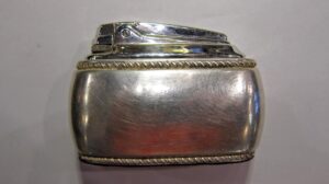 Stołowa zapalniczka marki Ronson z XX wieku, mosiądz, widok z boku na blacie.