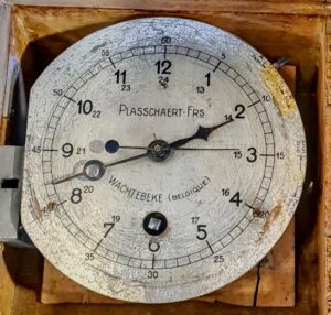 Zabytkowy belgijski zegar kontrolny lub minutnik przemysłowy firmy Plasschaert-Frs na tle.