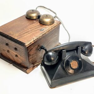 Zabytkowy zestaw telefoniczny Western Electric: dębowa skrzynka z dzwonkami i czarny telefon bakelitowy z korbką.