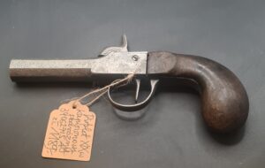Antyczny pistolet podróżny kapiszonowy z XIX wieku – widok z boku, ośmiokątna lufa, drewniana rękojeść.