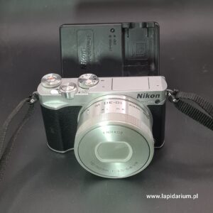 Aparat Nikon 1 J5 srebrny z obiektywem 1 NIKKOR 10-30mm na jasnym tle