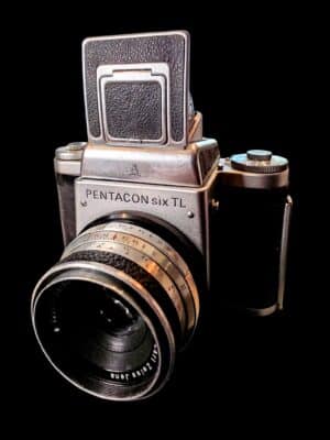 Kolekcjonerski aparat średnioformatowy Pentacon Six TL z obiektywem Carl Zeiss Jena Biometar 80mm na ciemnym tle.