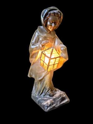Antyczna lampa figuralna z mosiądzu przedstawiająca postać w kapturze z latarnią, Kanada, początek XX wieku.